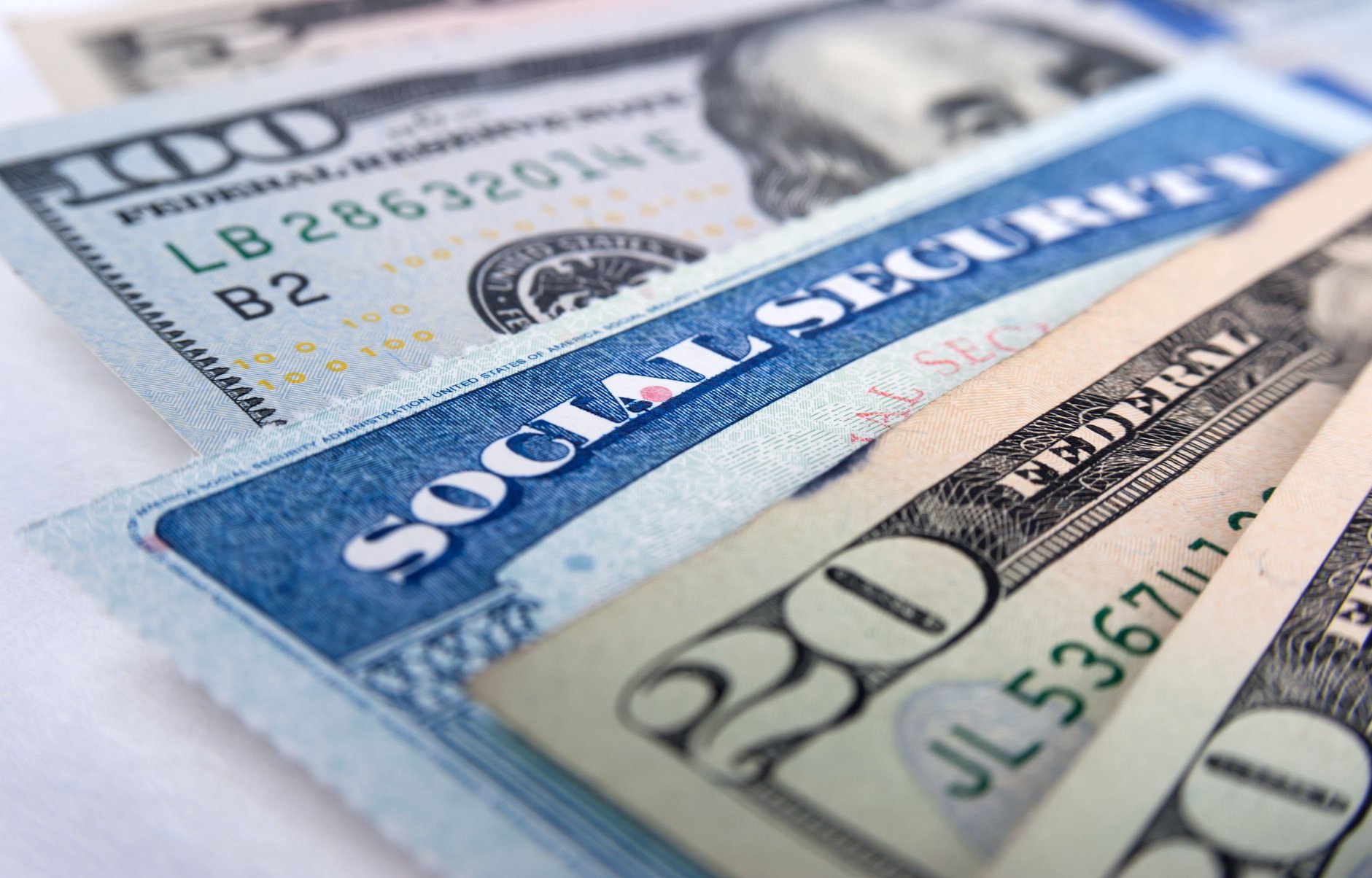 Social Security card layered over U.S. dollar bills, symbolizing retirement income and government benefits