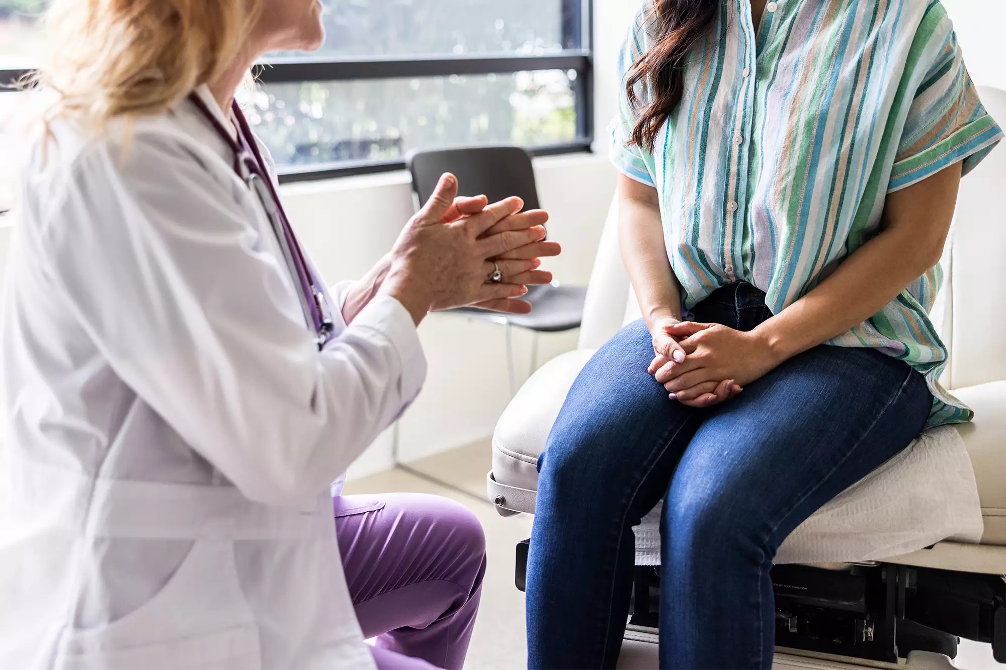 Female doctor talking with young woman in exam room, Getty Stock Image