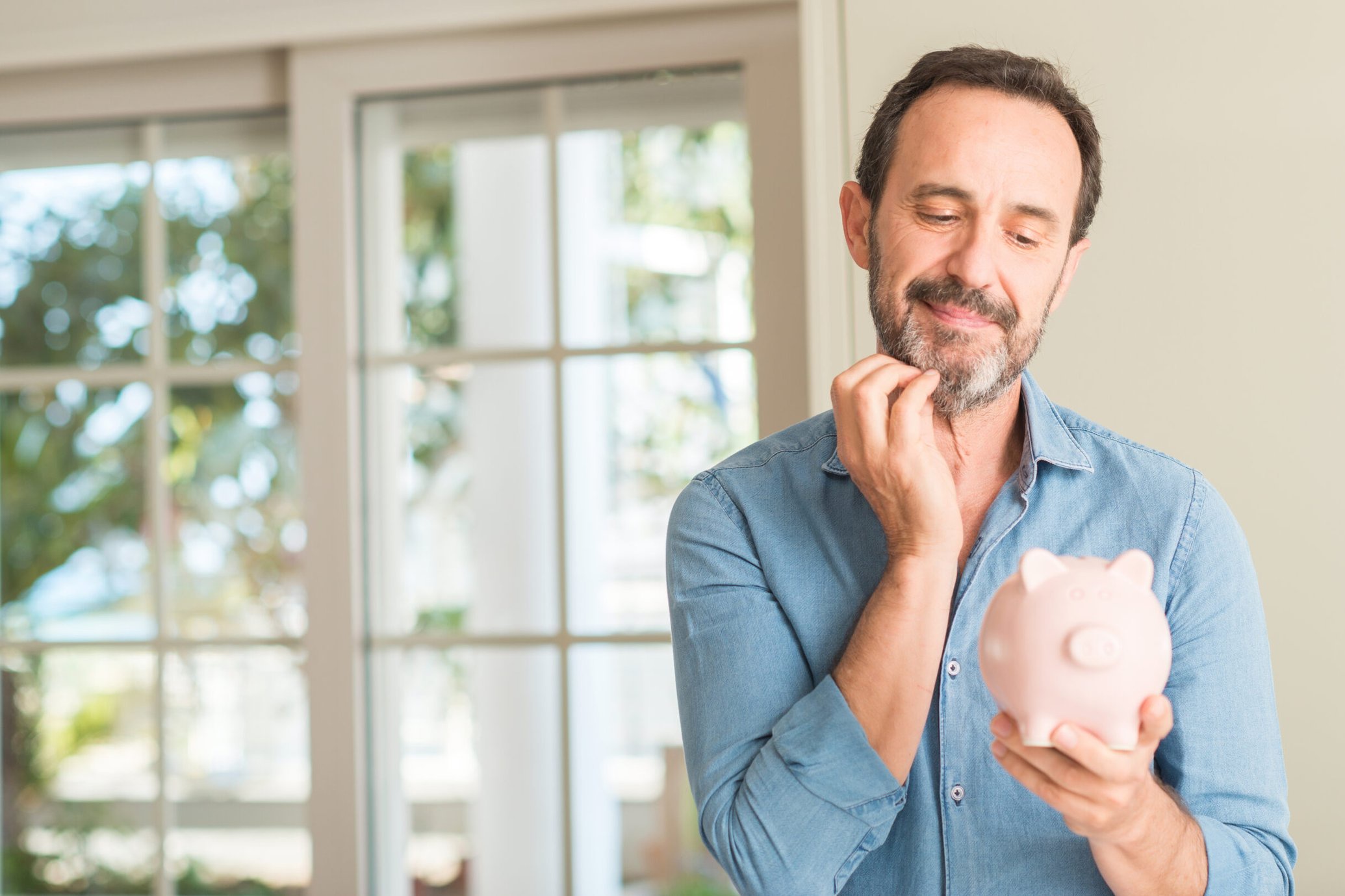 Curious man holding a piggy bank