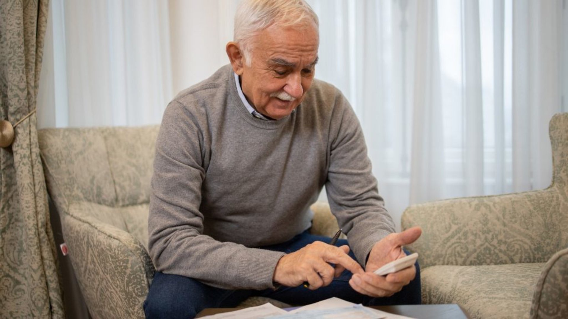 Discover a senior man using a calculator to do his taxes, rework budget and other financial tasks.