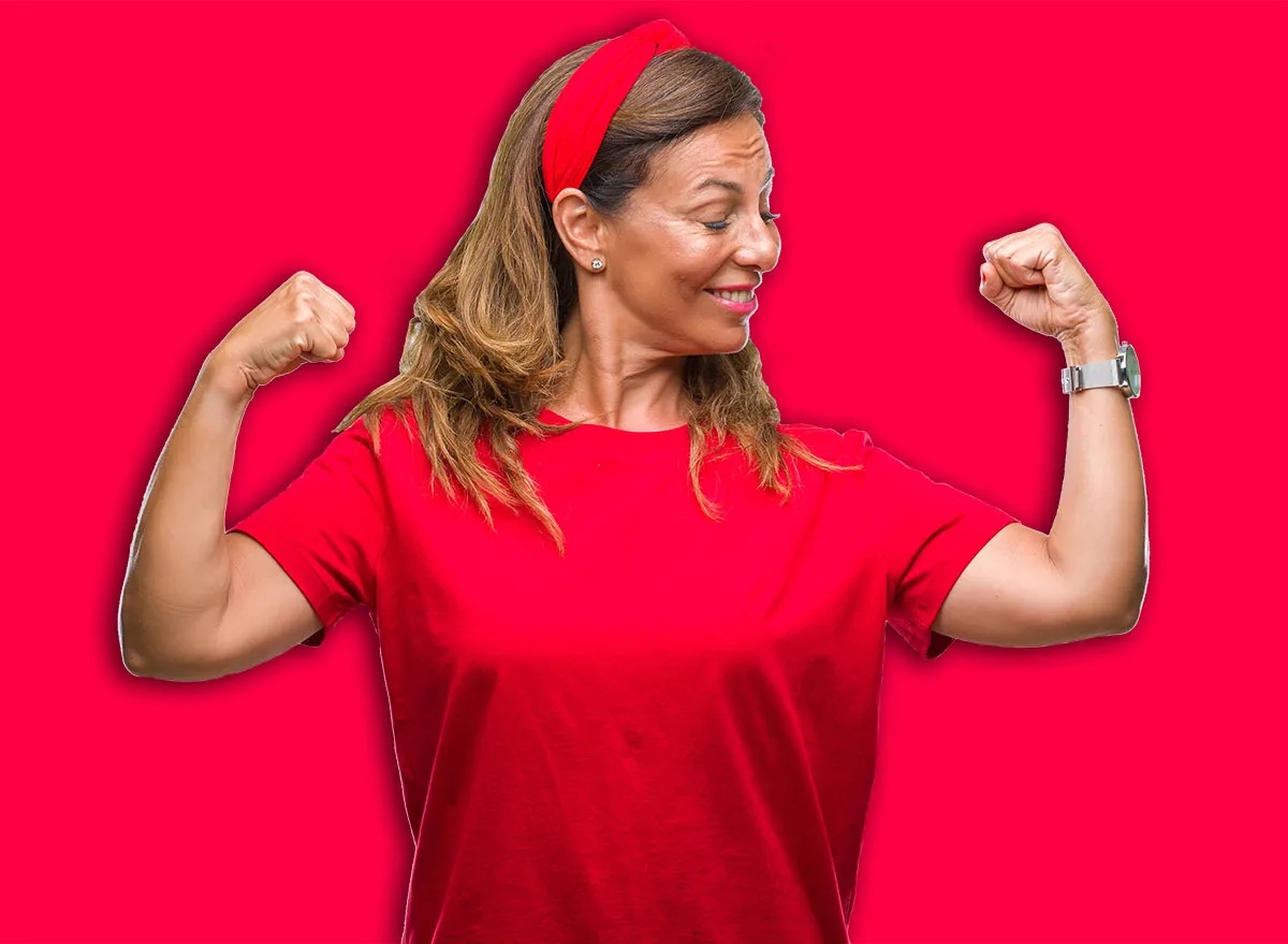 Middle age senior hispanic woman over isolated background showing arms muscles smiling proud. Fitness concept.