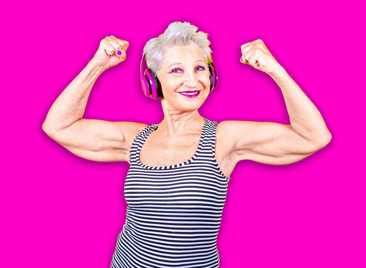 Senior grey haired woman athletic showing biceps showing powerful and pride smiling at camera positive on yellow background