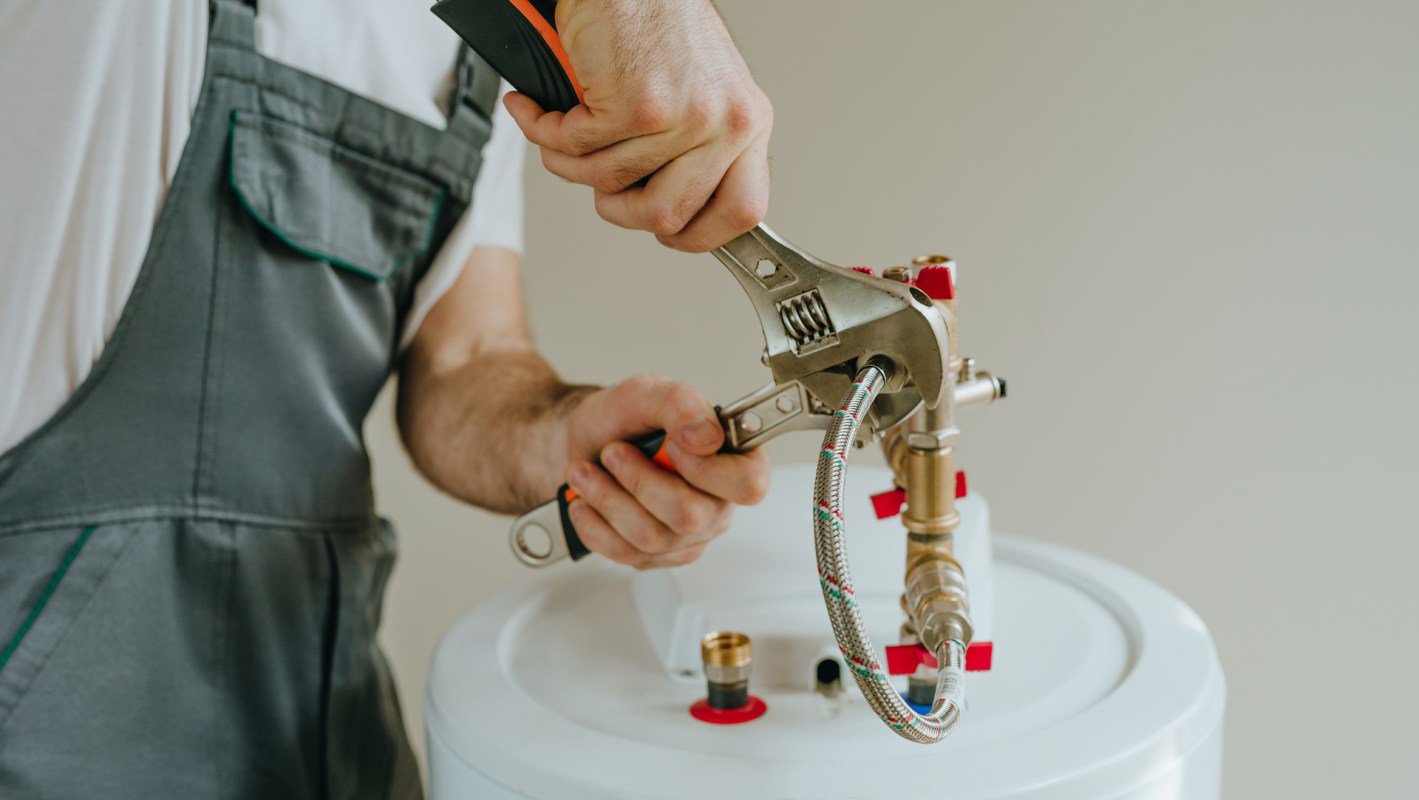 A person uses a wrench to work on plumbing equipment.
