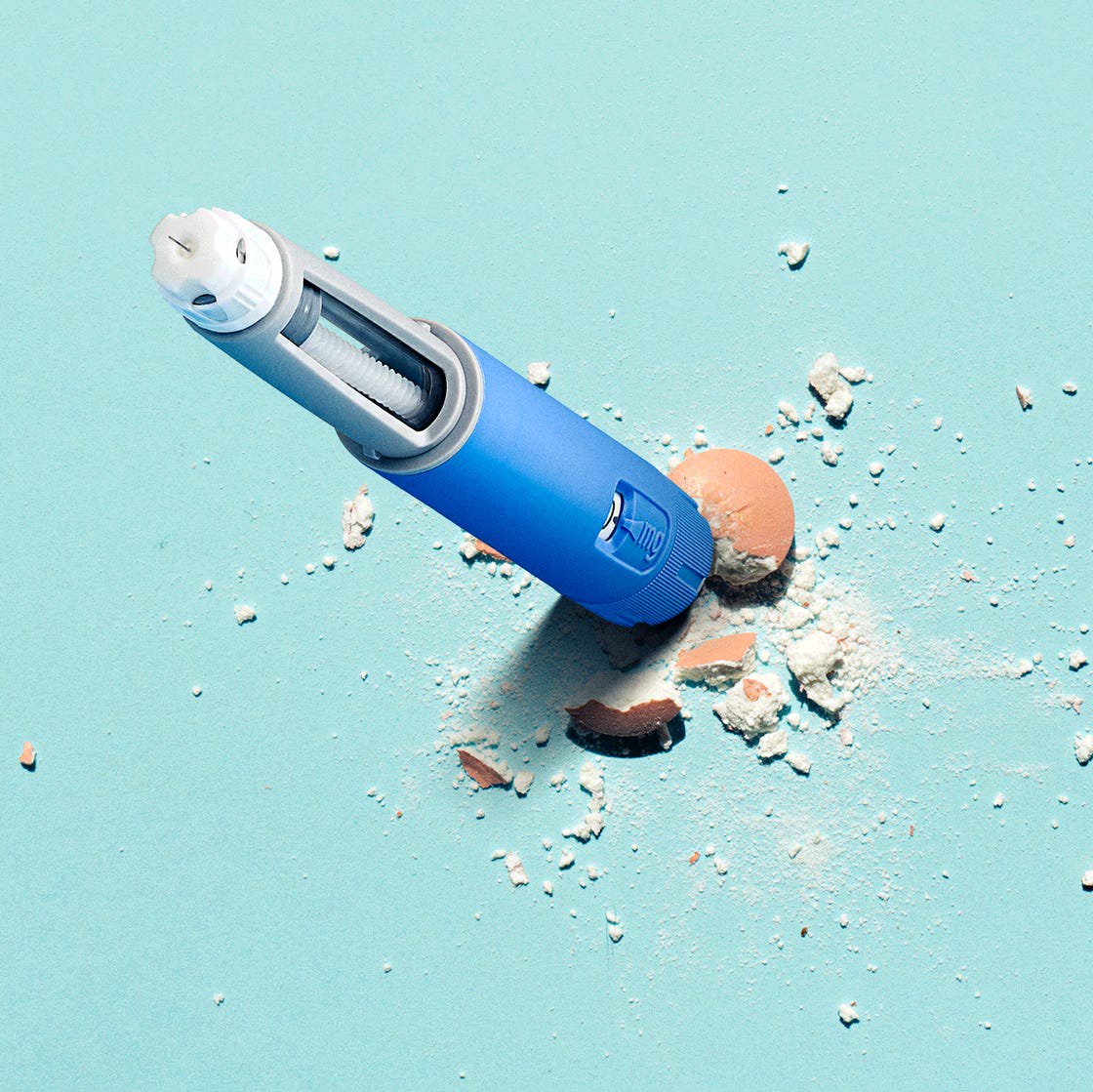 A blue powder dispenser with scattered crushed makeup on a turquoise background.