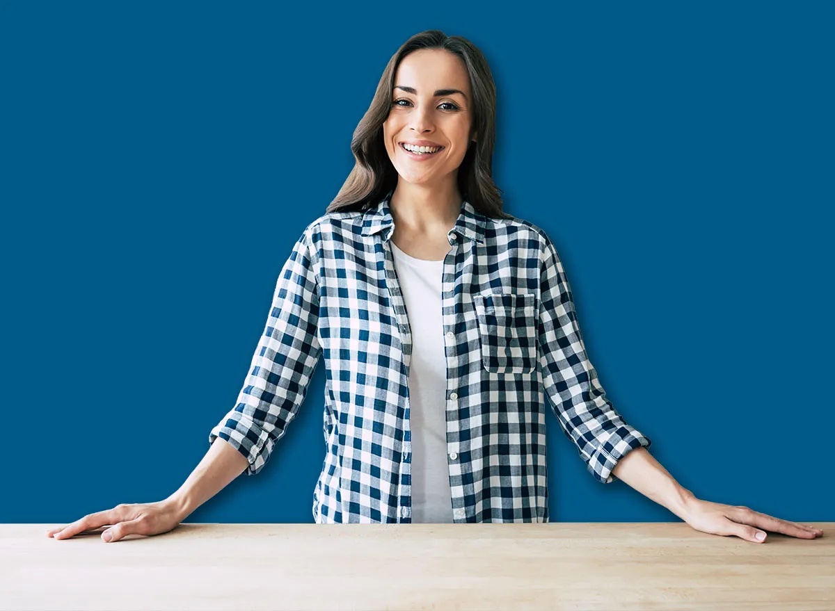 Young beautiful modern woman stands near table on kitchen at home.
