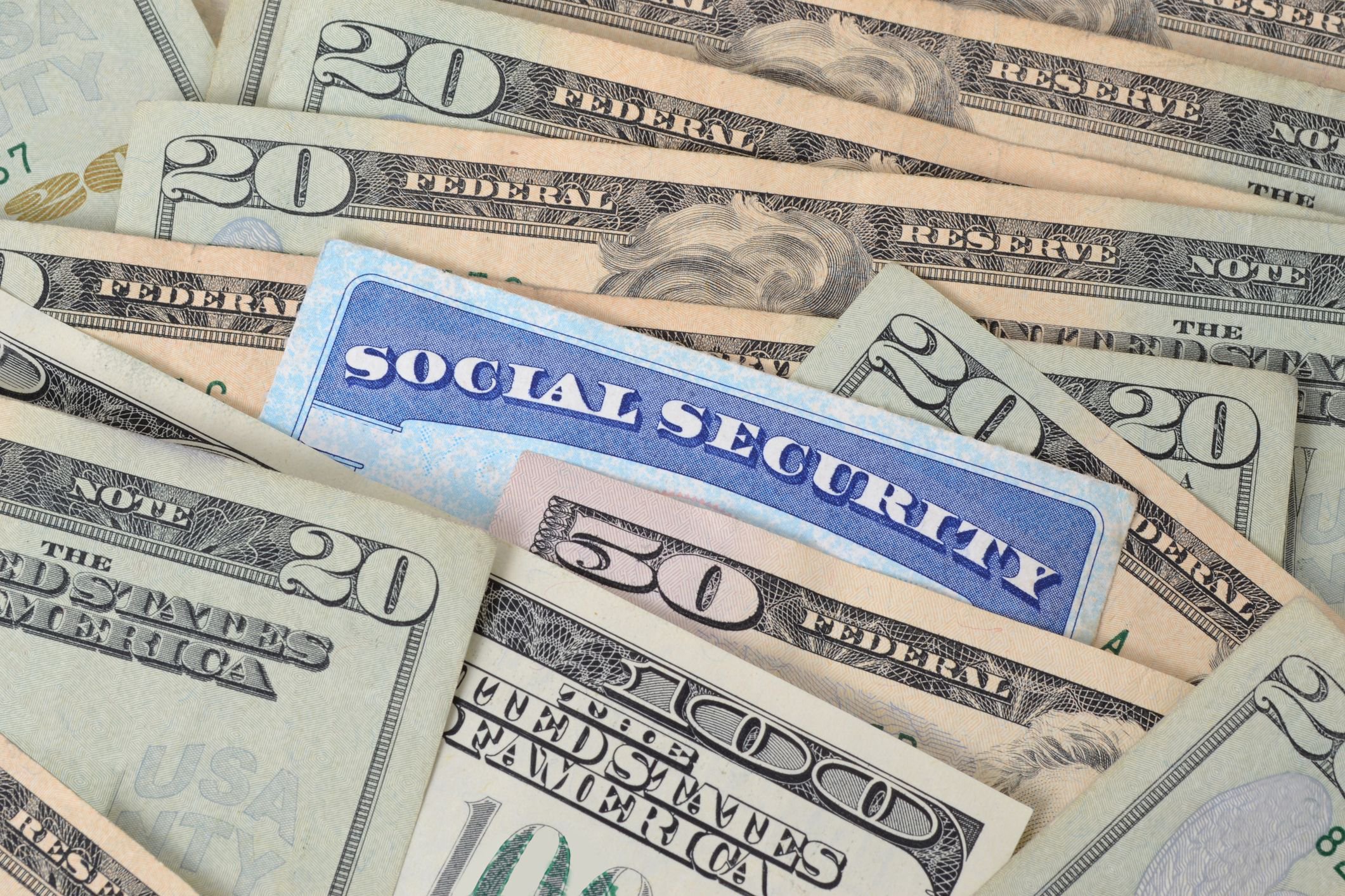 Social Security card surrounded by assorted U.S. dollar bills