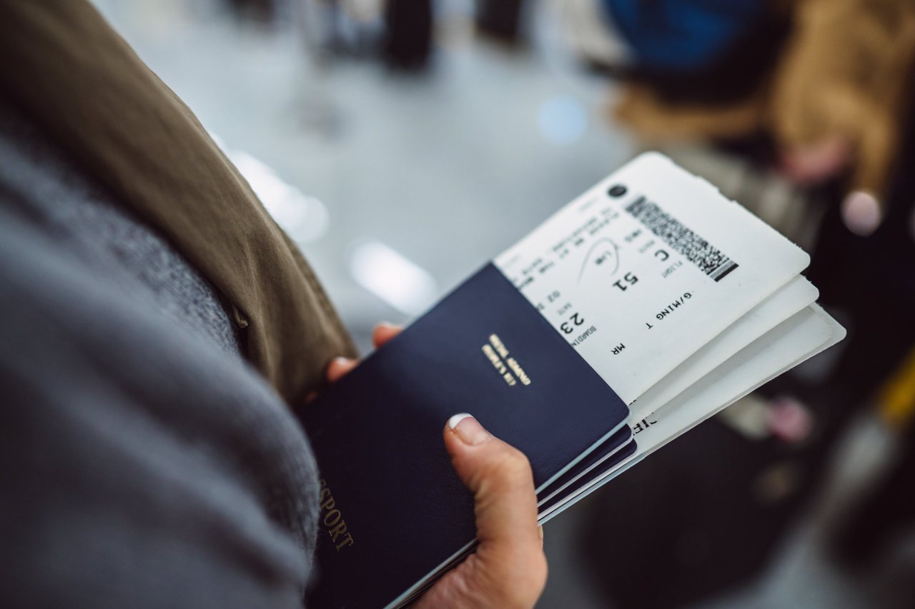 Person holding a blue passport and boarding pass at an airport