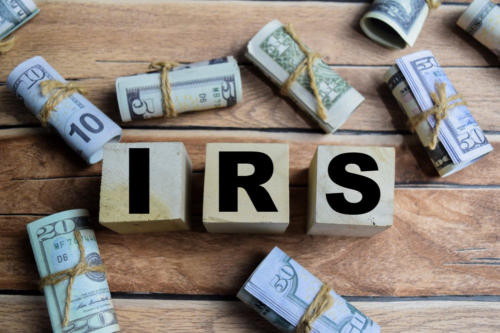 Wooden blocks spelling IRS surrounded by rolled banknotes