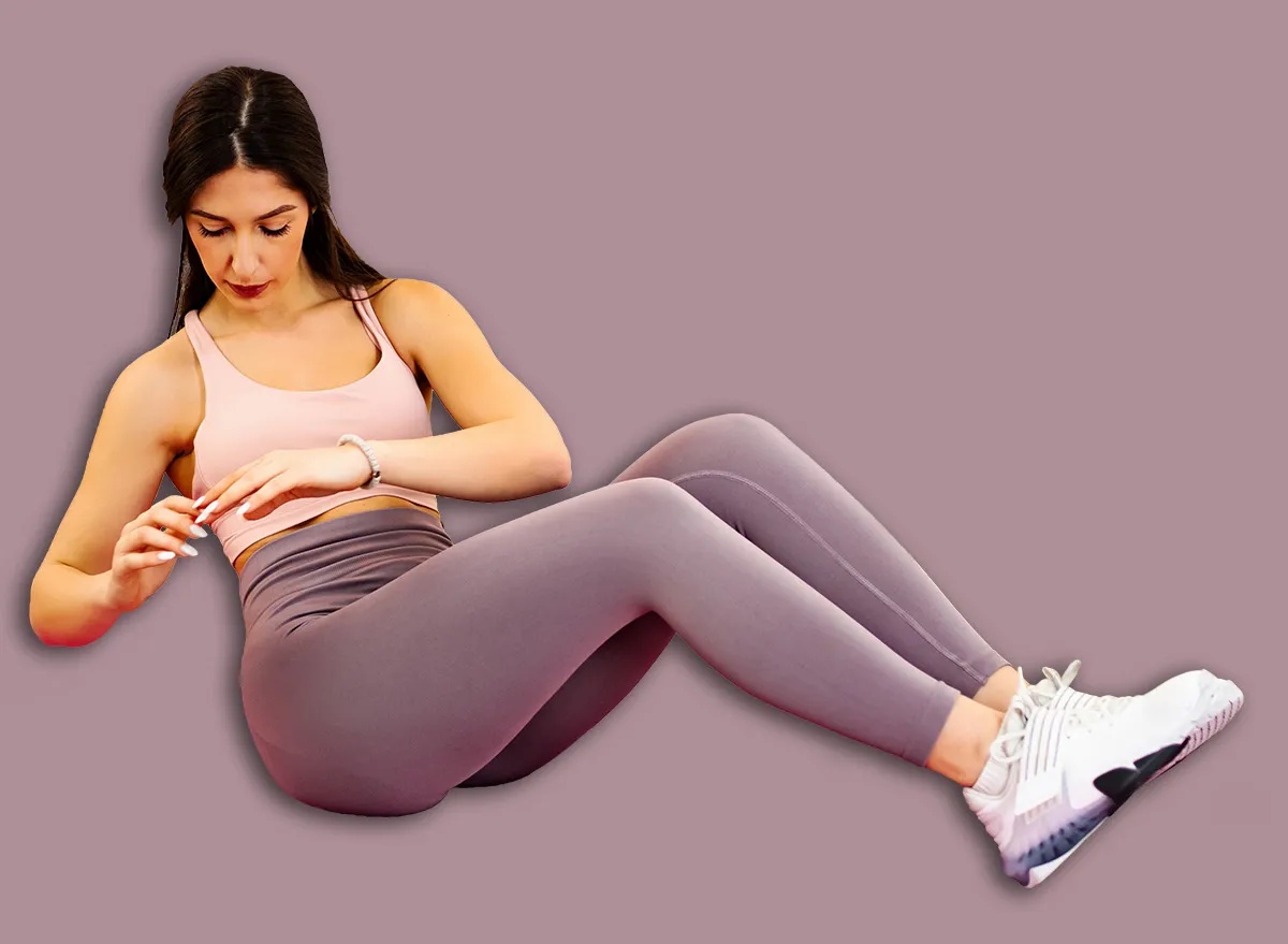 Woman doing Russian twists on yoga mat at home