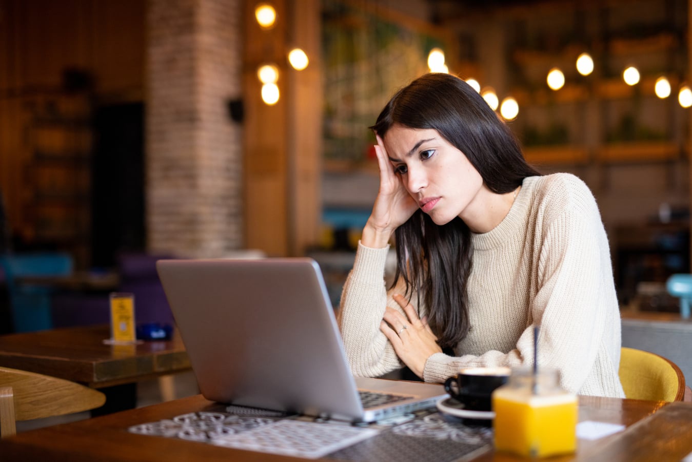 woman on Macbook frustrated at cafe