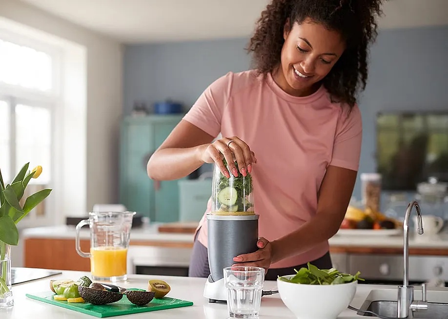 A woman at home making healthy juice drinks. — Monkey Business Images // Shutterstock