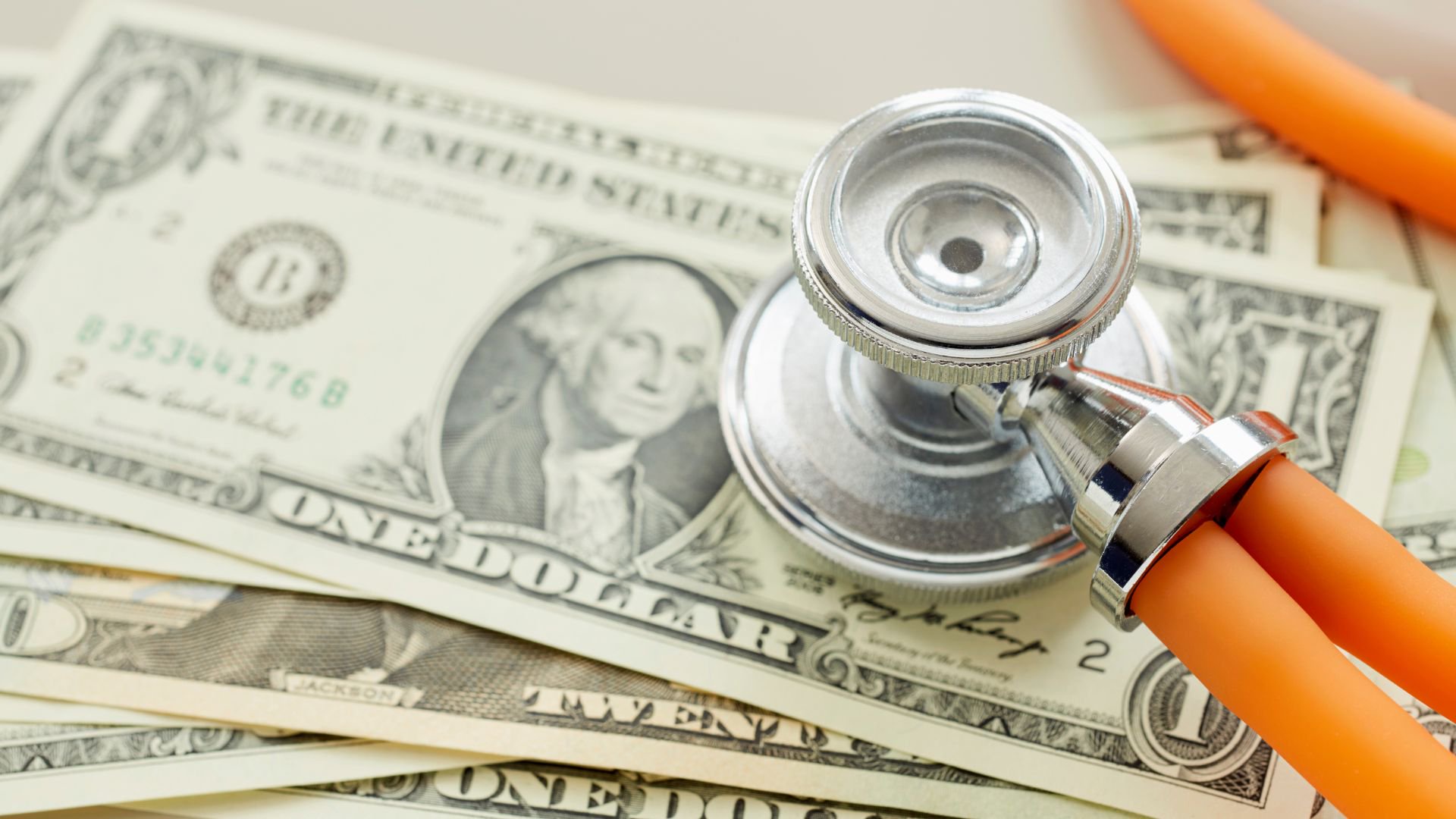 Discover a stethoscope resting on top of a stack of one-dollar US bills to showcase medical bills.