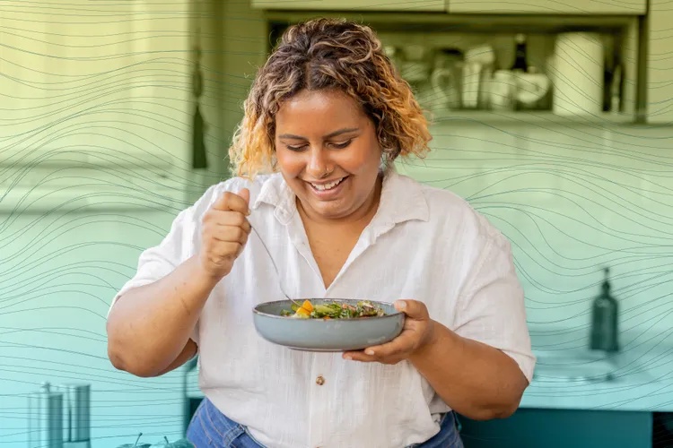 A person eating a salad in a kitchen