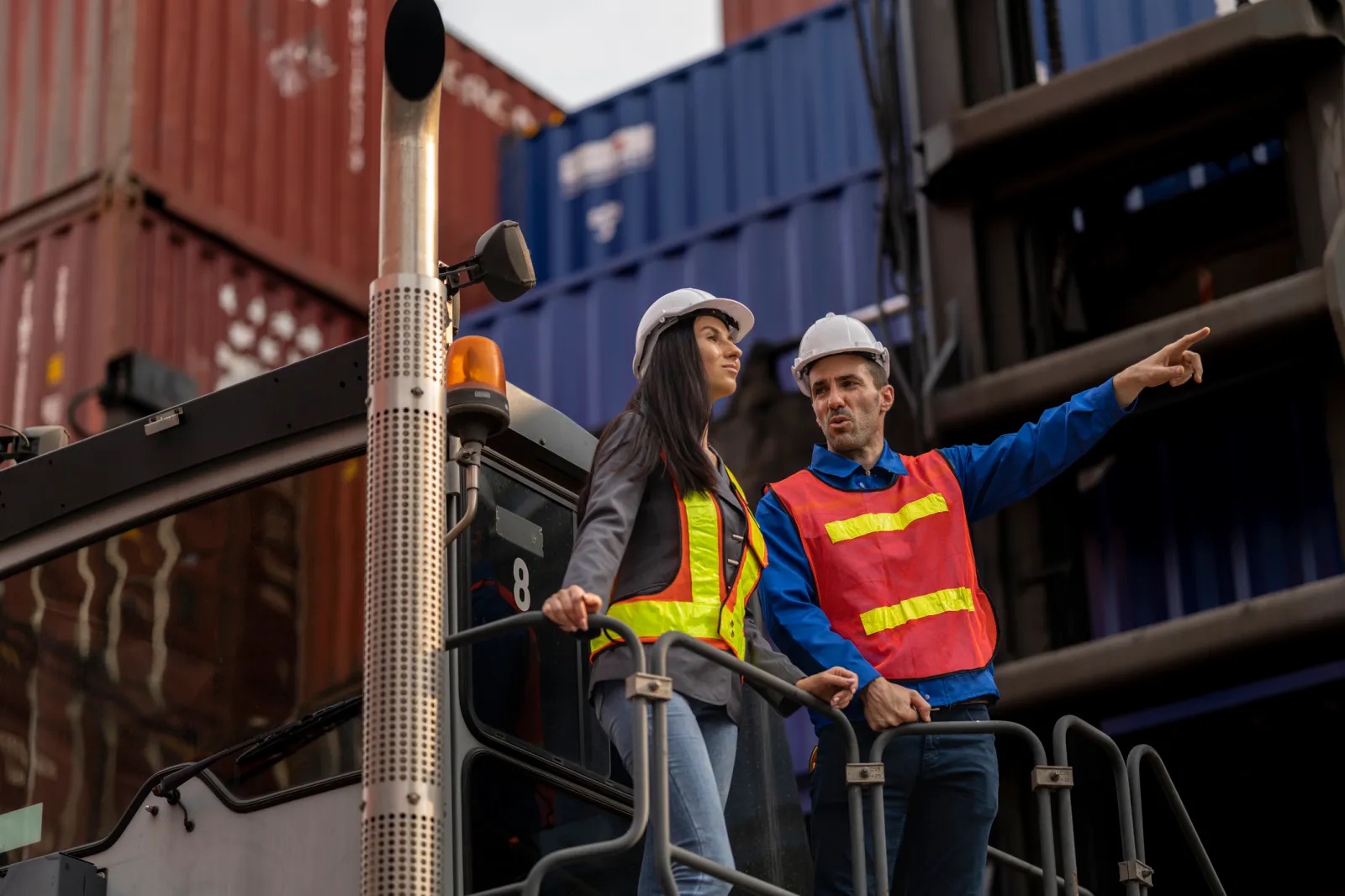 Workers discuss operations at a shipping container yard.