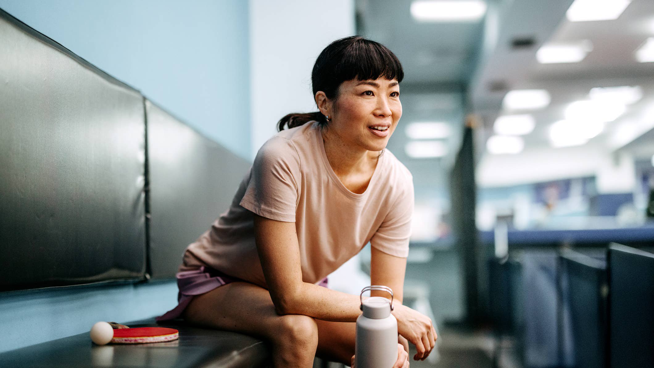 Woman sitting down on bench after a workout.