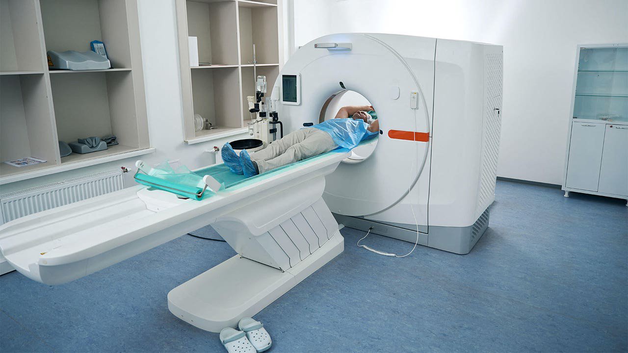A photo of a mature man lying in a CT scanner.