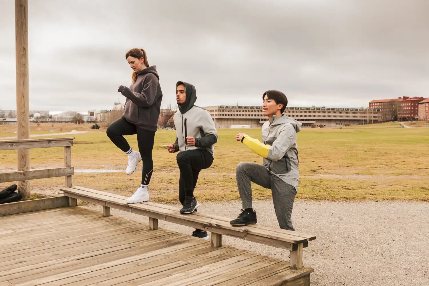 Three friends cheering each other on as they do step ups at an outdoor gym.