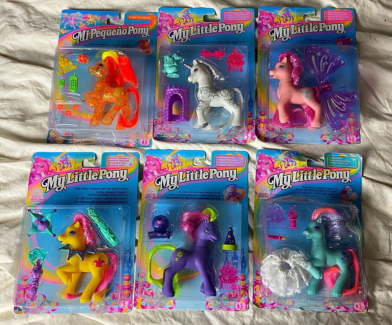 Six My Little Pony toys in colorful packaging, each featuring a different pony figure with accessories. The packages are arranged in two rows of three on a white surface.