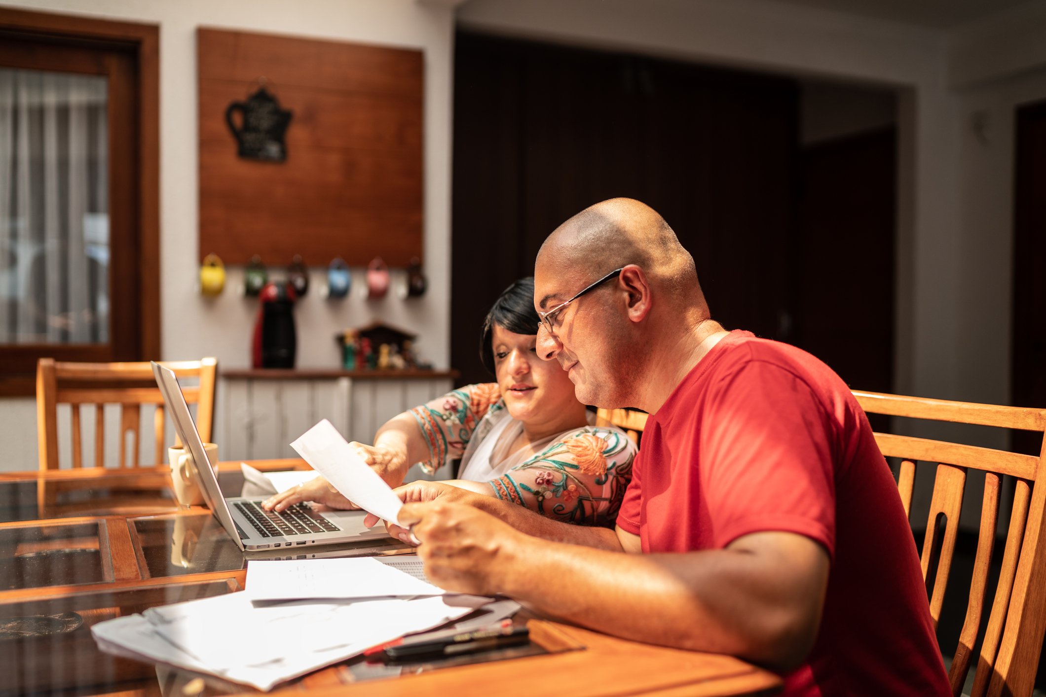 Adults looking at financial paperwork in their home.