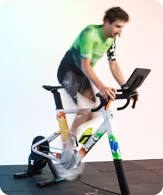 A person in motion riding an exercise bike with a colorful design and tablet mounted on the handlebars.