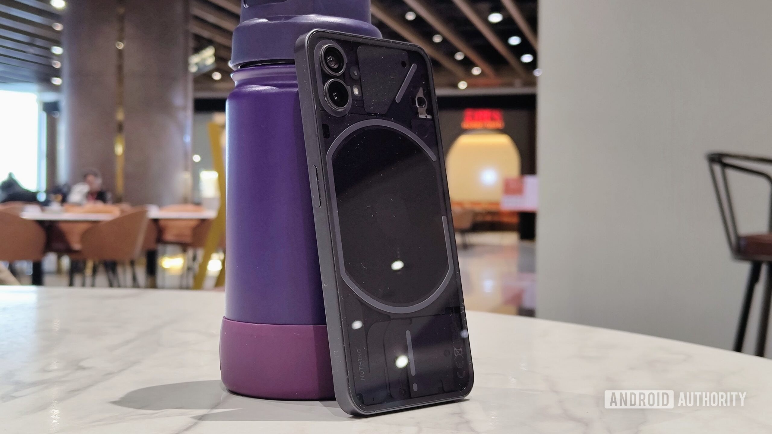 Nothing Phone 1 standing upright against a water bottle.