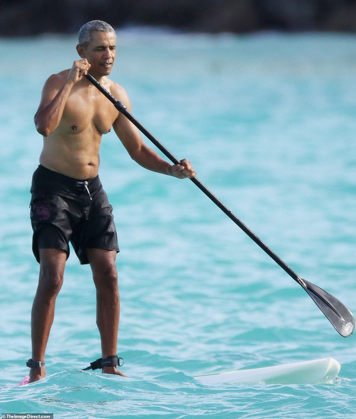 Shirtless Barack Obama shows off his fit physique during a paddle board session while on vacation in Hawaii (Photos)