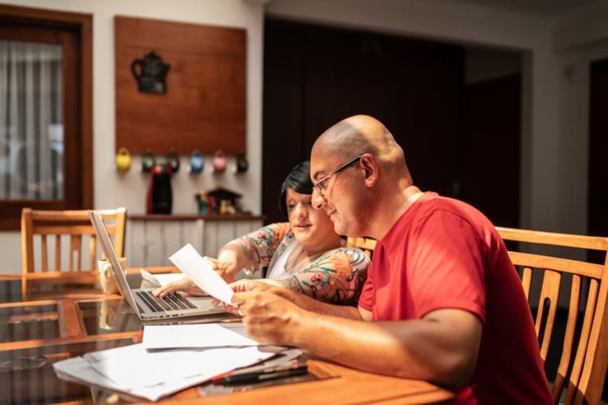 Adults looking at financial paperwork in their home.