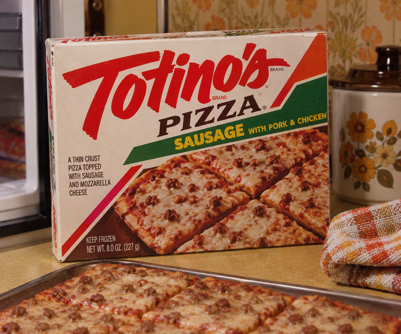 A Totino’s Pizza box labeled sausage with pork and chicken sits next to a baked pizza on a tray in a retro kitchen. A checkered cloth is visible on the counter.