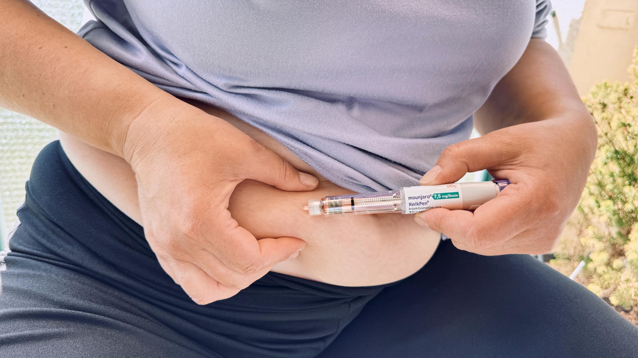 A woman self-injects a Mounjaro KwikPen into her abdomen for diabetes management and weight loss.
