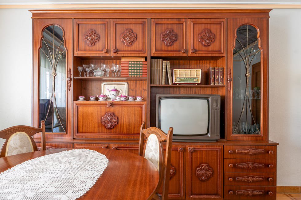 Old fashioned living room with wooden furniture and vintage television showing decorating trends from the 1980s