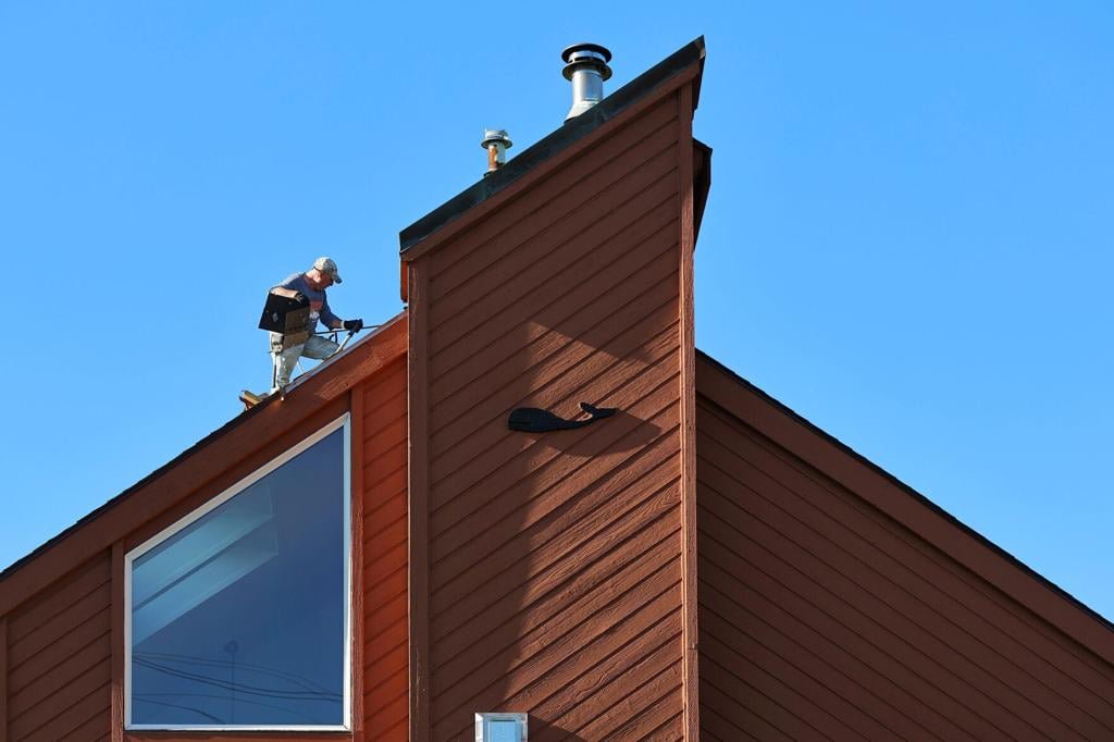 On October 7, 2026, a roofer removes shingles from a house in New Bedford, MA that features a whale decoration, before putting