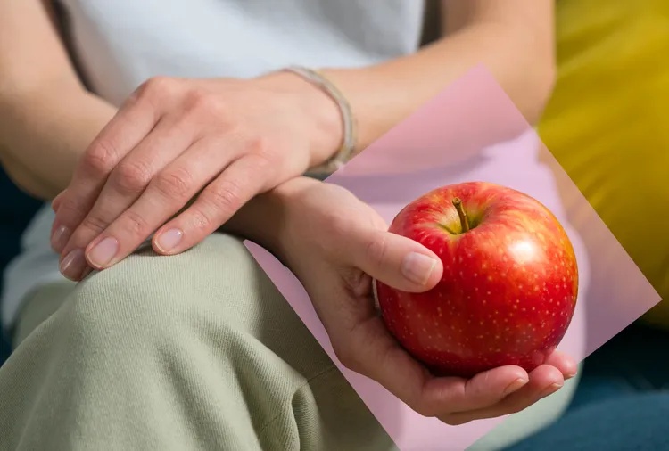 Person holding an apple seated with crossed legs