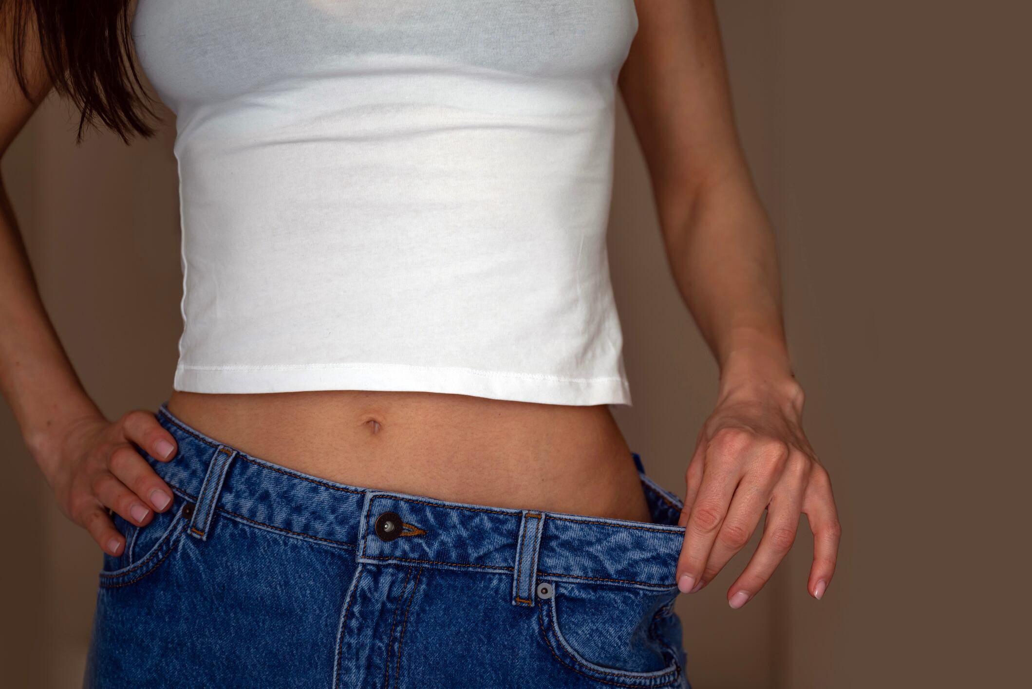 Woman with jeans showing weigh loss.