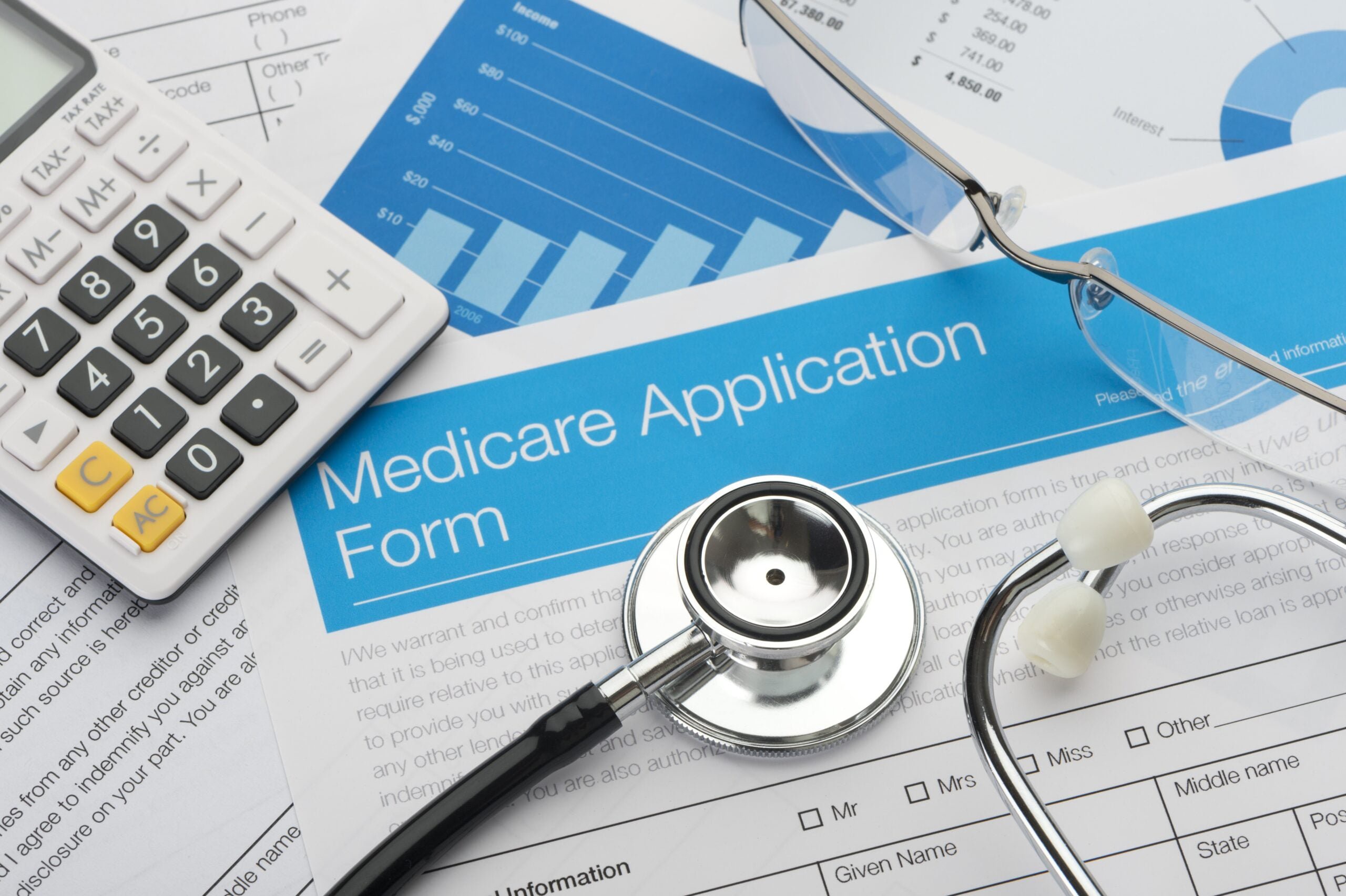table with medicare application forms and a stethoscope on top. Expenses retirees should review.