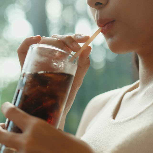 Close-up of a woman enjoying a refreshing glass of cola