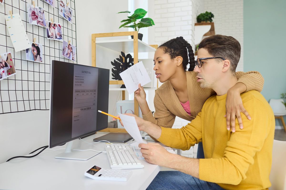 Couple checking electricity bill on computer. They set budget, payment and finance, planning monthly expenses and saving with documents. Clear home budgeting and saving theme for couples.