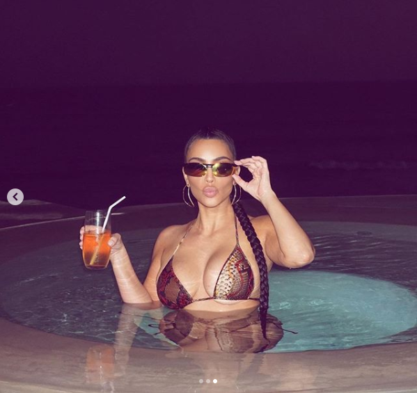 Kim Kardashian flaunts her famous curves in tiny snakeskin bikini during a racy night swim (Photos)