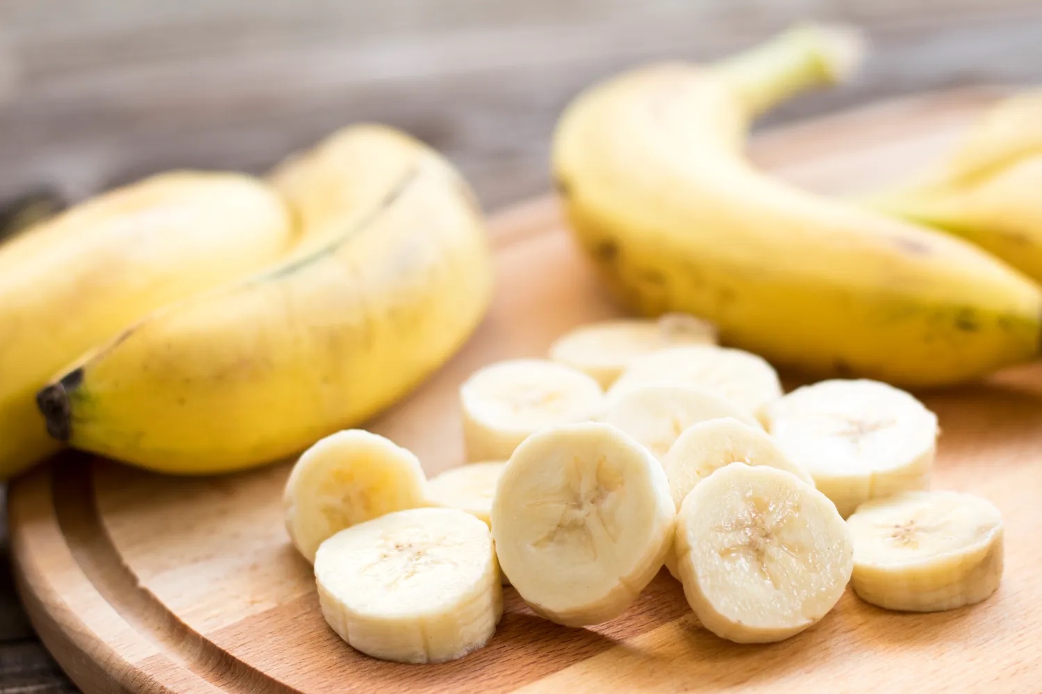 Whole and sliced bananas on a wooden surface