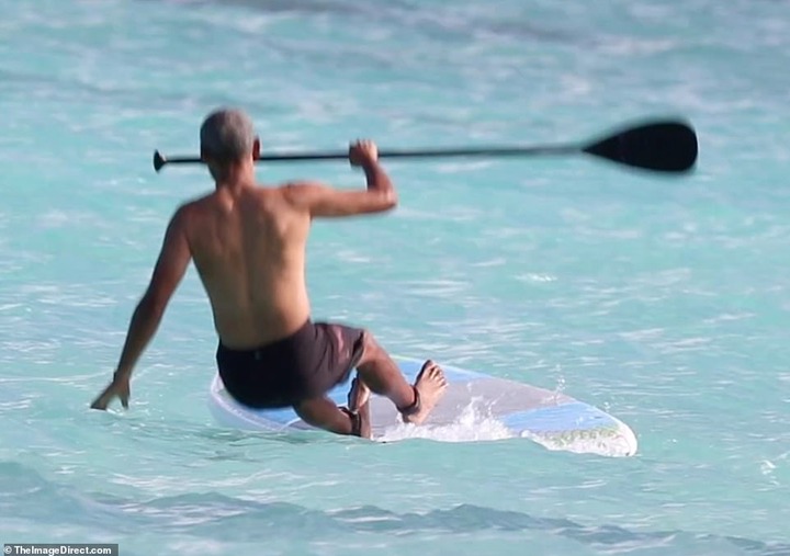 Shirtless Barack Obama shows off his fit physique during a paddle board session while on vacation in Hawaii (Photos)