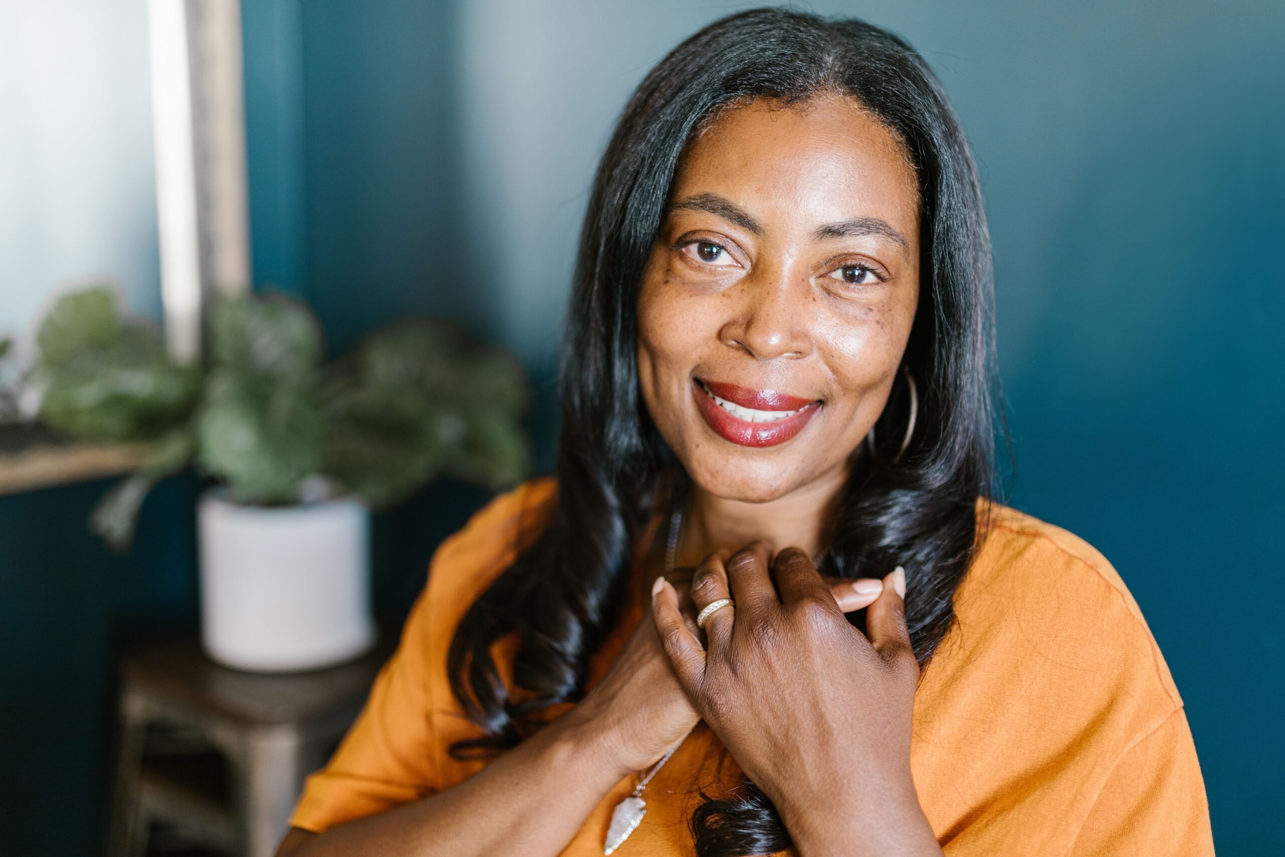 Beautiful portrait of a smiling African American woman wearing an orange top, indoors.