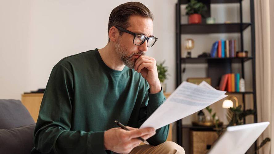 middle-aged-man-concentrating-on-financial-documents-and-a-laptop-at-home