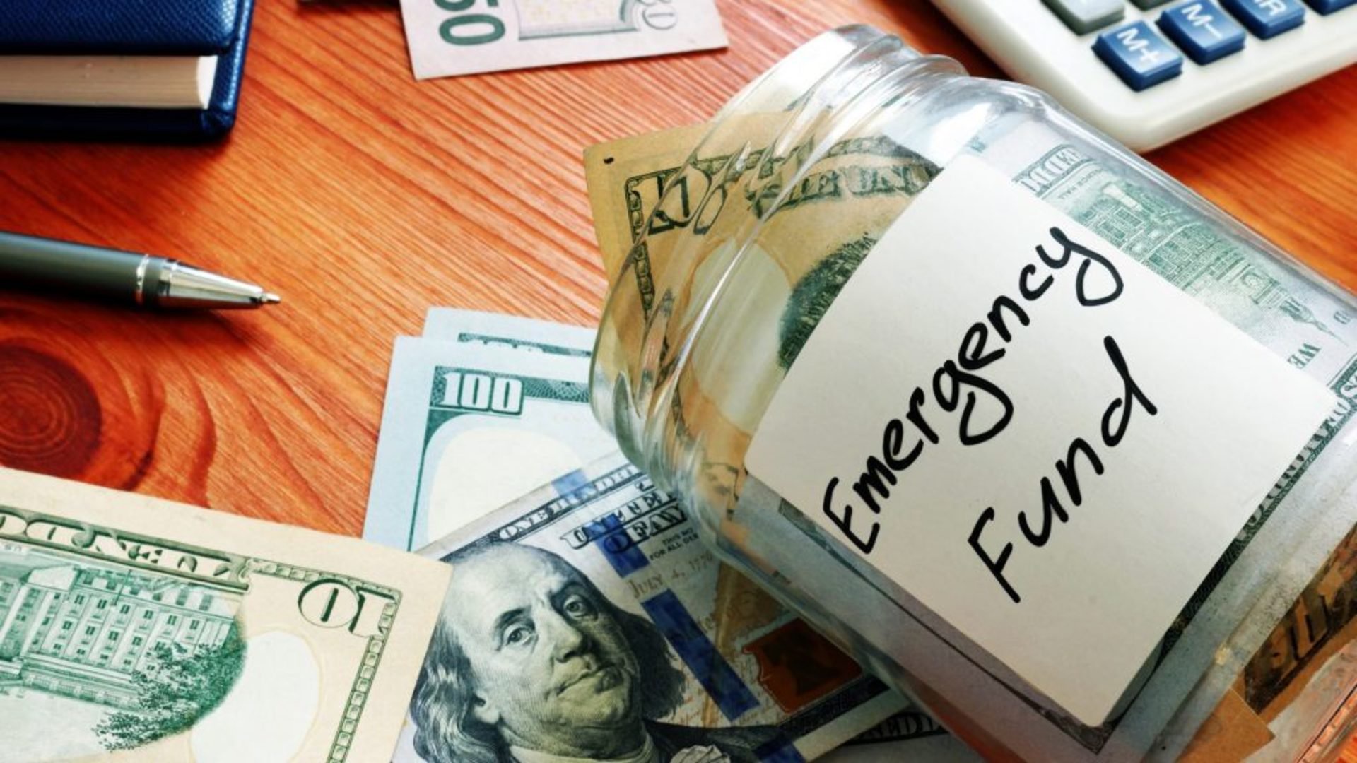 Discover a glass jar labeled emergency fund filled with various paper bills and coins for someone's savings