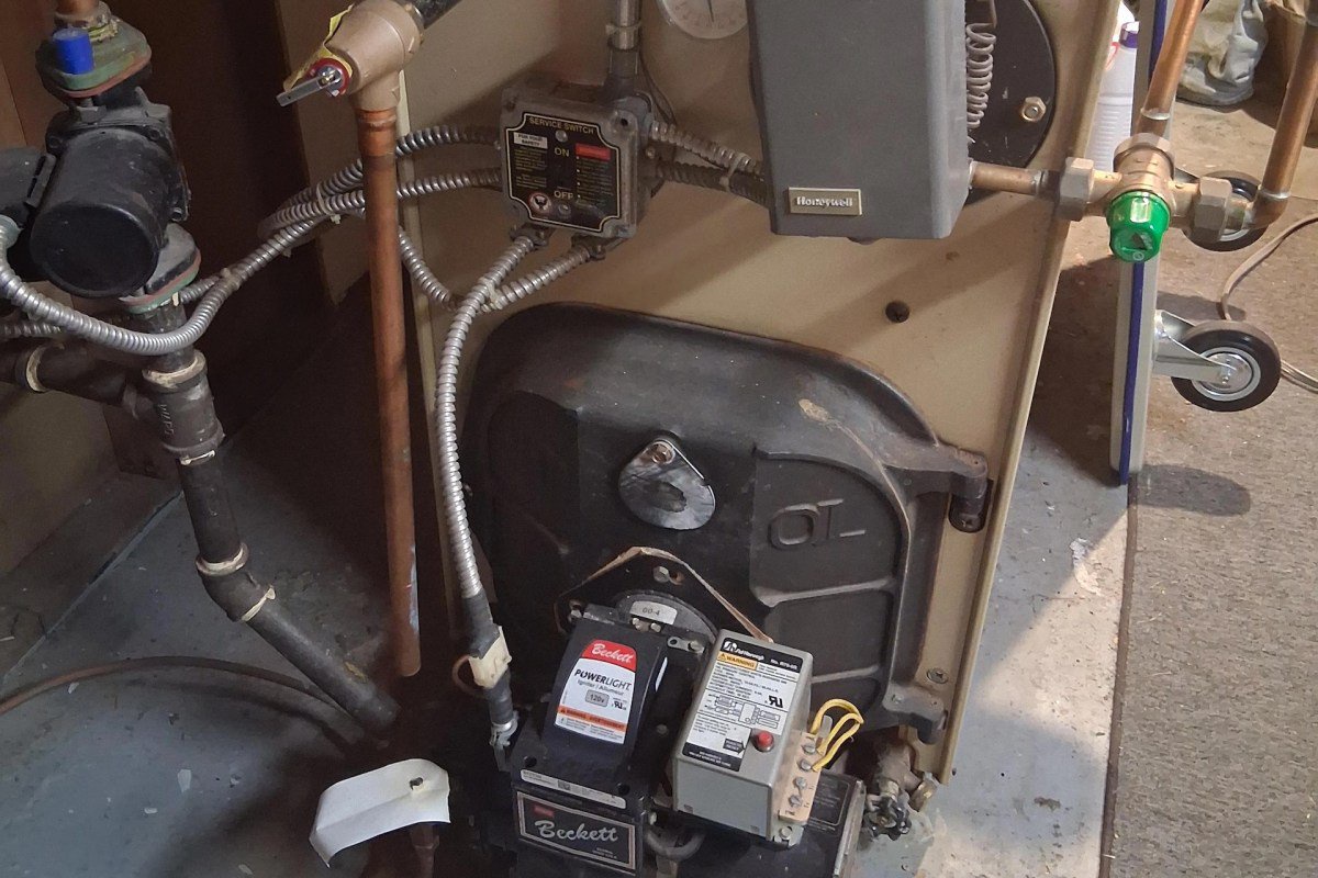 A heating system with valves, wires, and a control box in a basement setting.