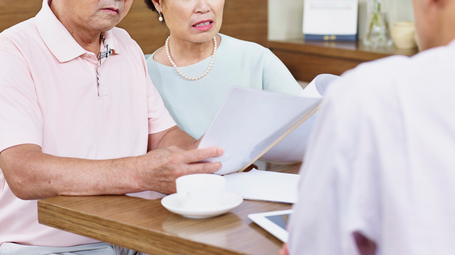 An elderly couple reviews documents at a table.