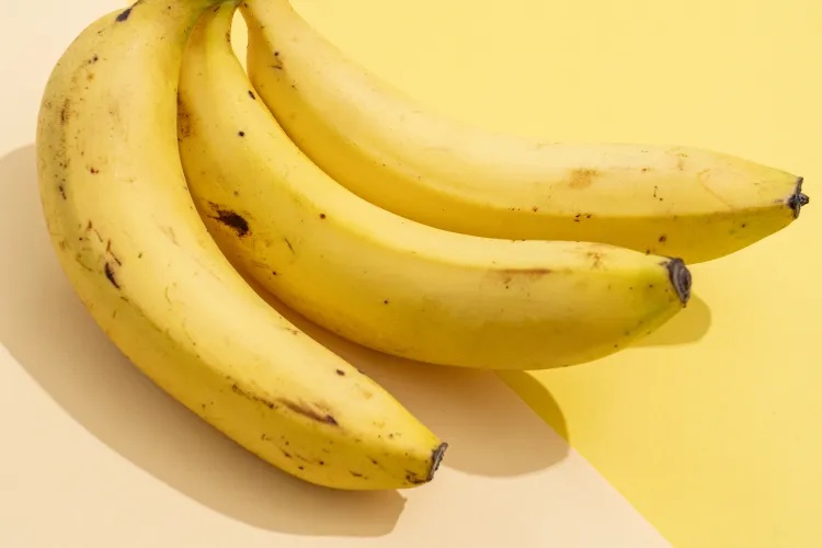 A cluster of ripe bananas on a yellow background