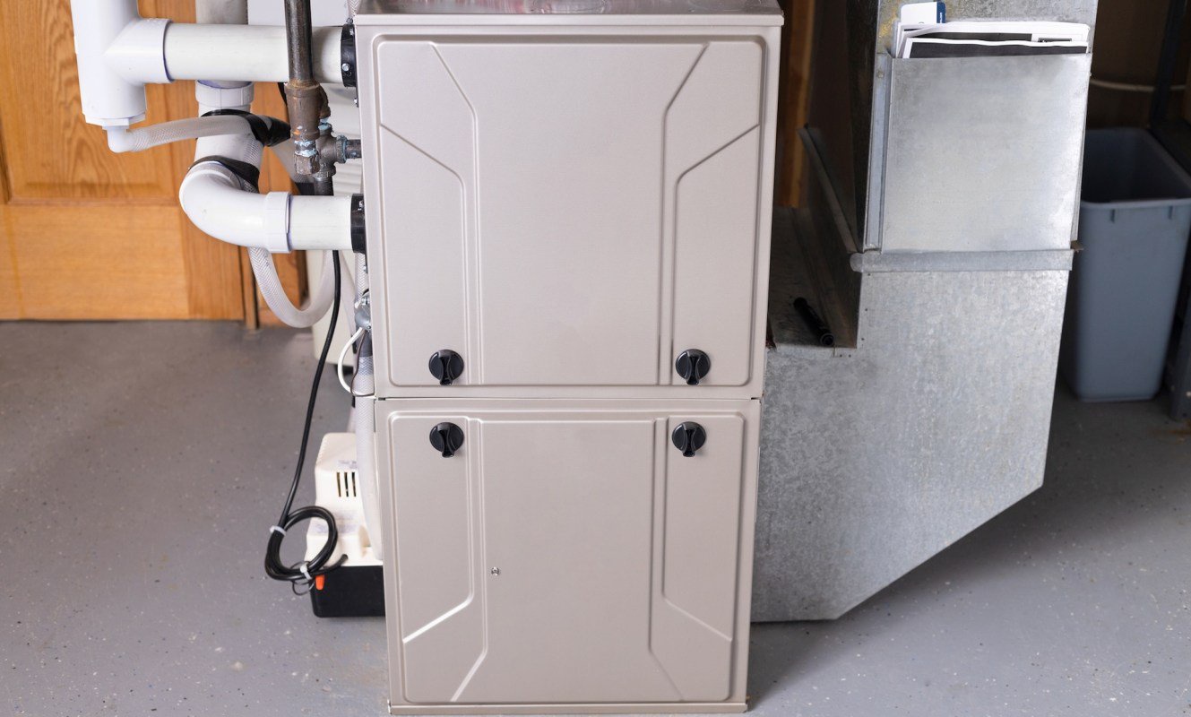 A beige utility cabinet situated next to a metal duct in a basement setting.