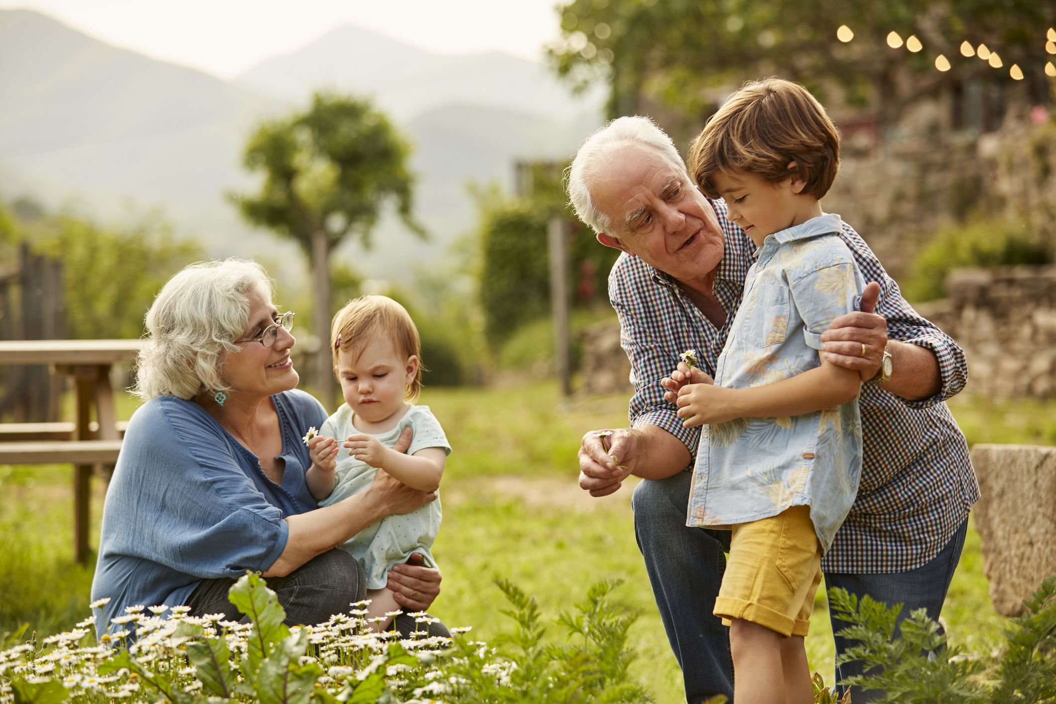 Grandparents talking to children. Family having leisure time in yard. They are wearing casuals. holiday expenses for retirees.