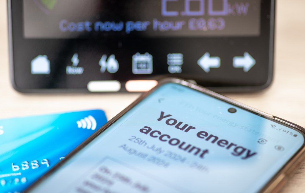 A smartphone displaying an energy bill, a bank card, and a smart energy meter.