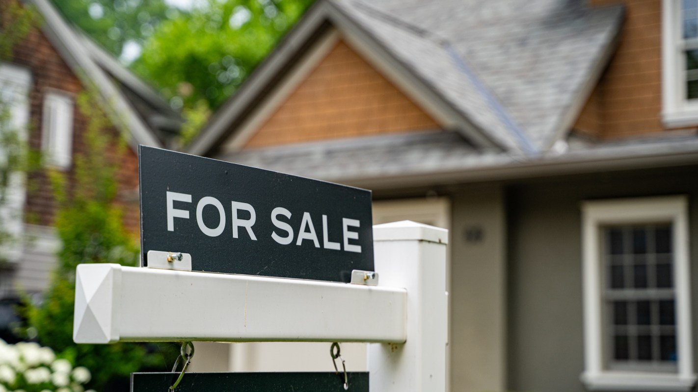 A "For Sale" sign in front of a house.