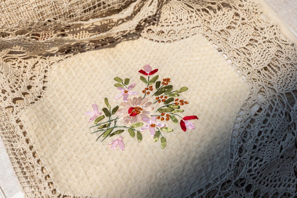 A close-up of linen fabrics featuring colorful floral embroidery with braid